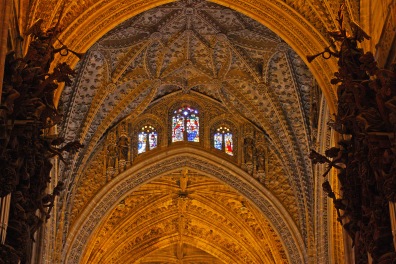 A gothic looking interior wall flanked by sculptures of trumpeting angels.